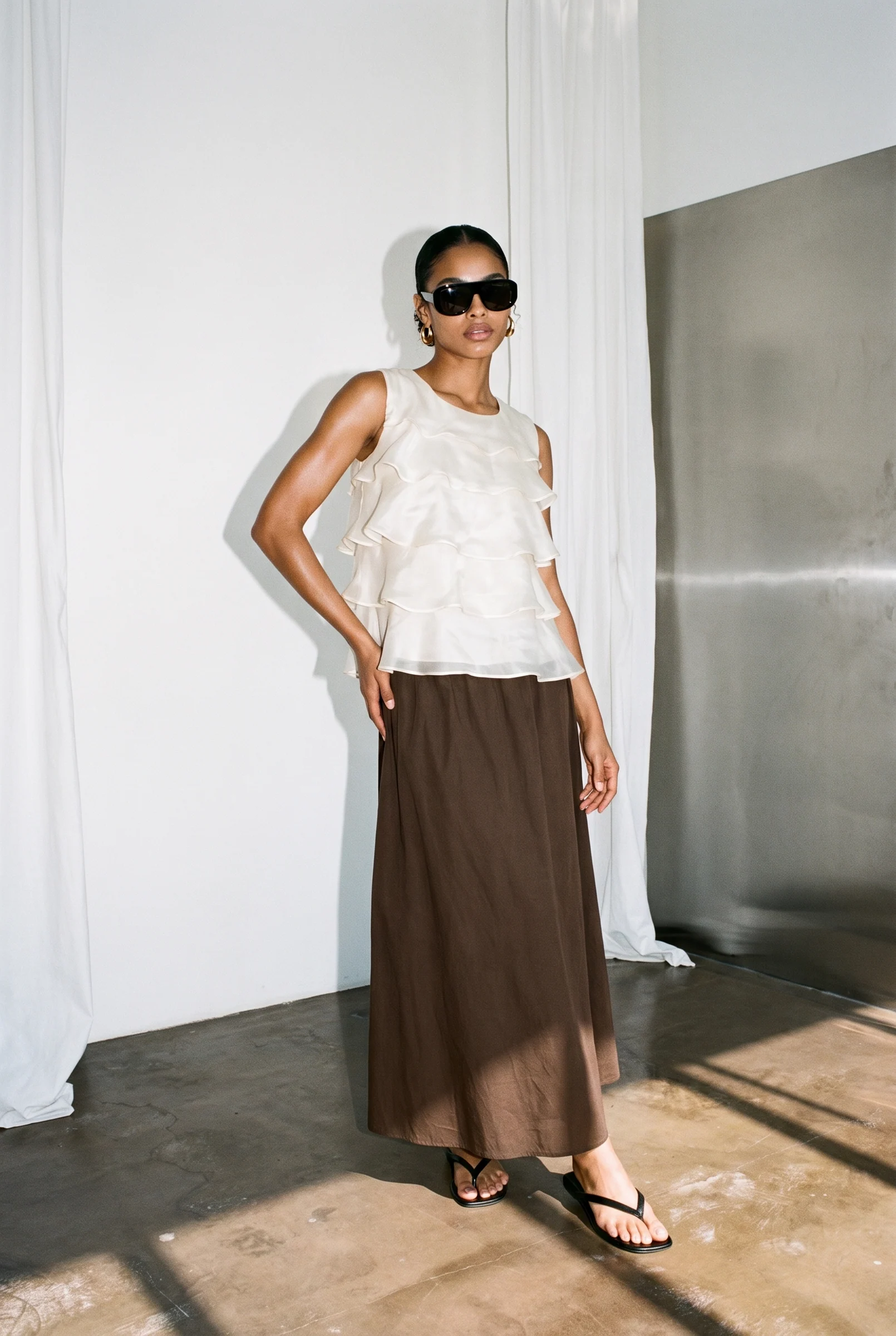 Full length: the ivory top with a brown maxi skirt in a studio with a steel wall