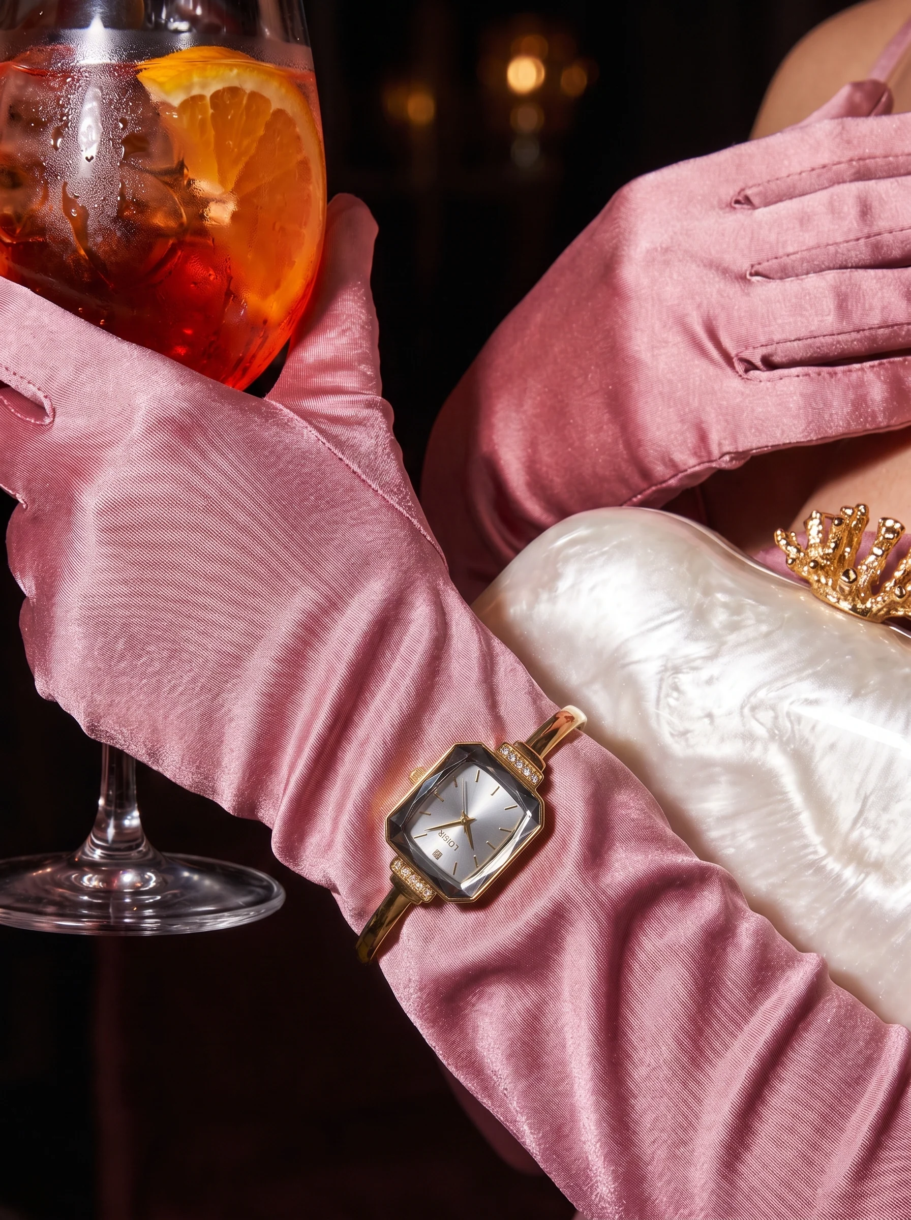A gloved hand resting on a pearl clutch, the watch at the wrist, a spritz behind